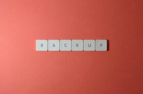 Free Close-up of keyboard keys spelling 'BACKUP' placed on a coral-colored surface. Stock Photo