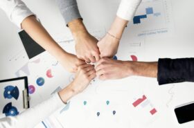 Free Colleagues celebrate success with a fist bump over financial charts depicting teamwork and unity. Stock Photo
